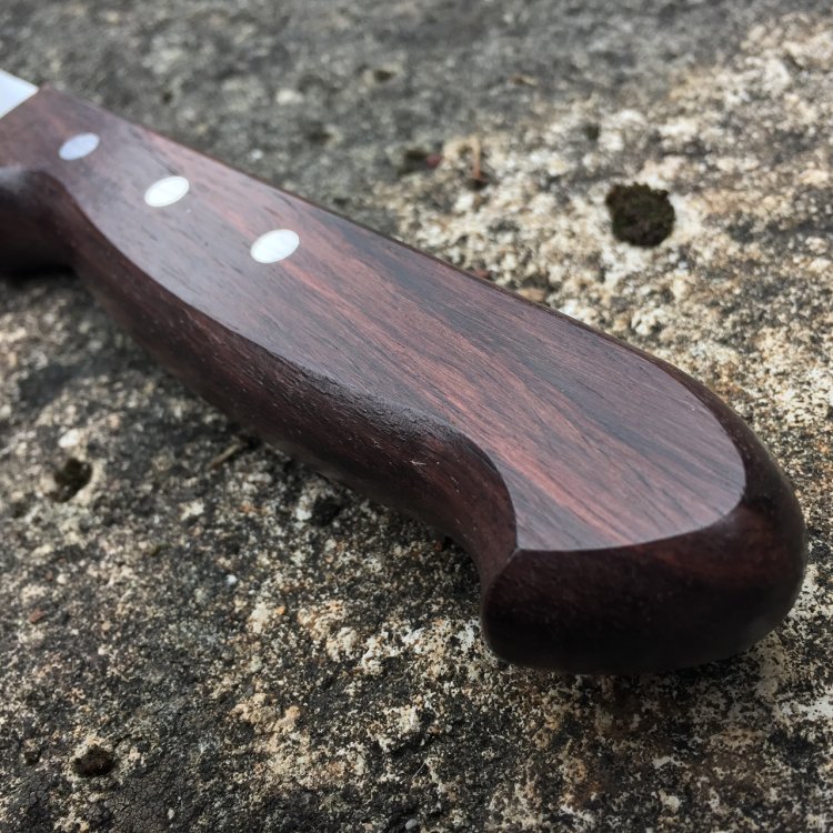 Edler Holzgriff des PanoramaKnife Brotmessers liegt auf einem Stein