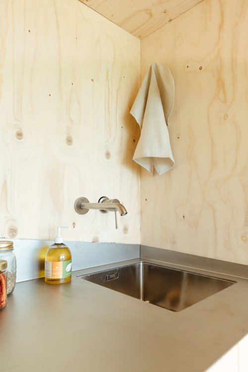 Abwaschbecken in einem Holzhaus mit Leinentuch, dass in der Ecke hängt.