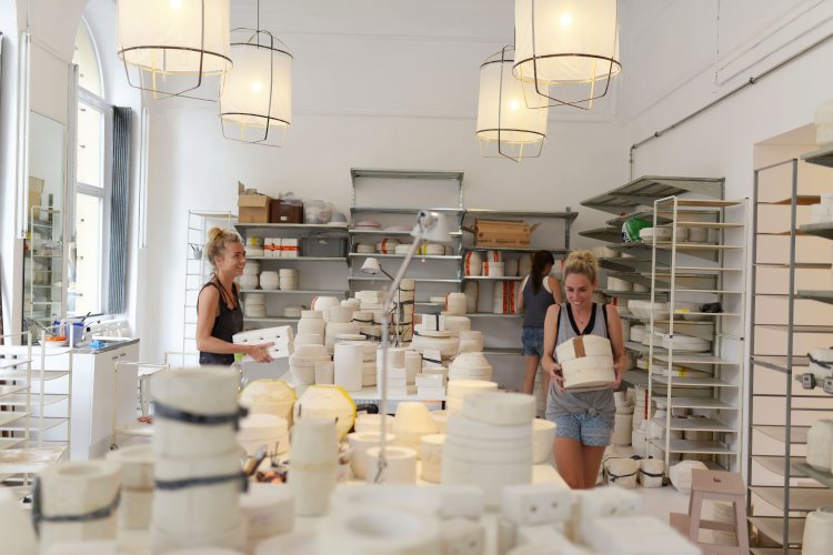 Ladenansicht mit zahlreichen Keramikobjekten im Vordergrund und zwei Frauen im Hintergrund