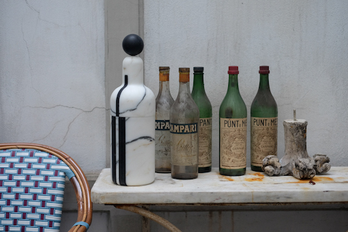 Weisser Marmorbehälter aus der Reihe Coolers von Editions Milano auf einem Tisch mit alten Campari-Flaschen