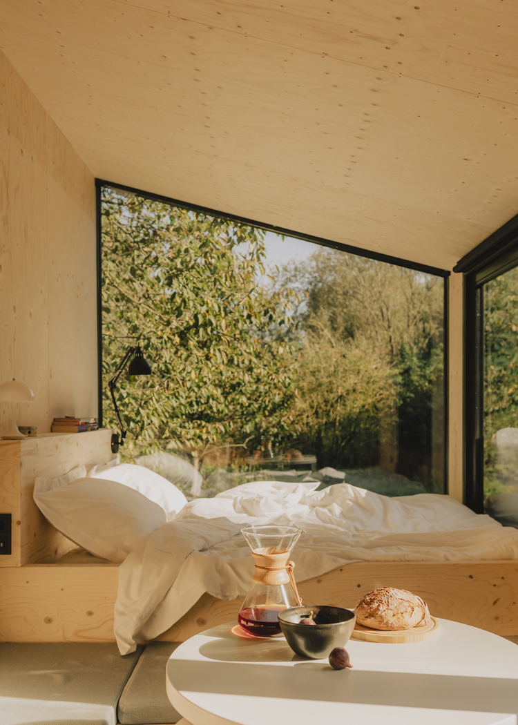 Innenansicht Cabin mit Bett und Blick durch Panoramafenster in die Natur