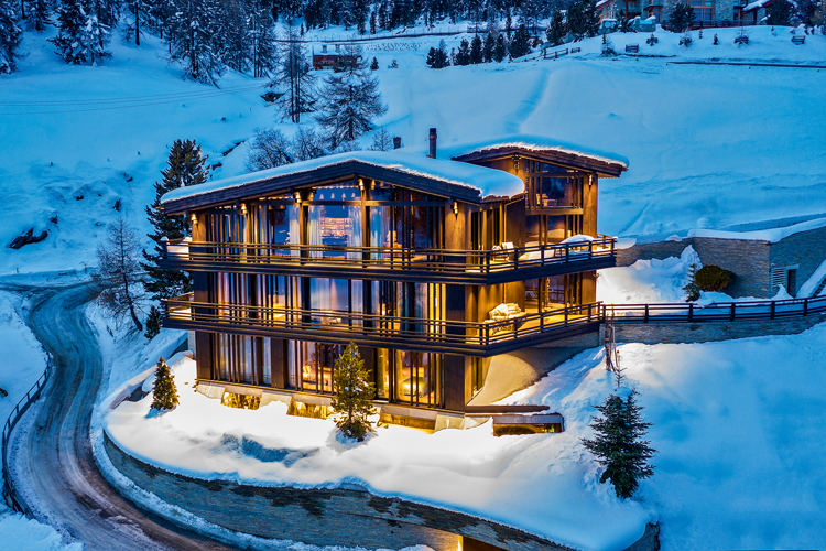 Aussenansicht von einem modernen dreistöckigen Chalet in der Winterlandschaft von St. Moritz.