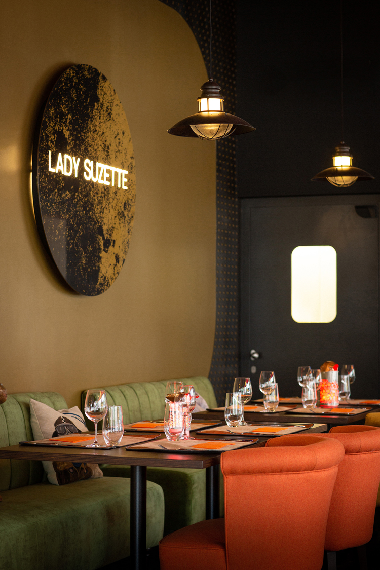 Innenaufnahme des Restaurants Lady Suzette an der Langstrasse orangen Polsterstühlen und grünem Sitzsofa.