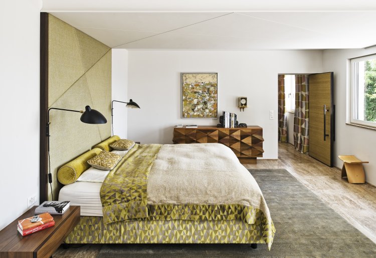 Schlafzimmer mit olivfarbenem Bettbezug und Kopfteil.