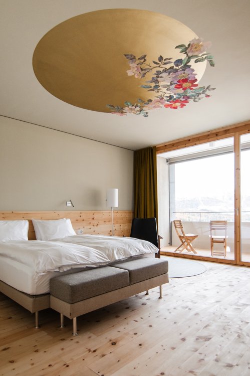 Aufnahme eines Hotelzimmers mit Blick aufs Bett und floraler Deckenverkleidung.