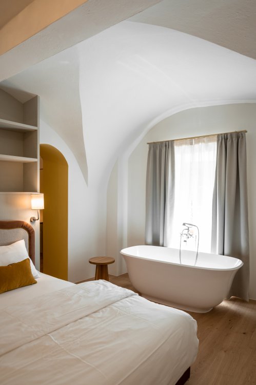 Hotelzimmer in der Pension Leuchtenburg mit freistehender ovaler Badewanne vor Fenster.