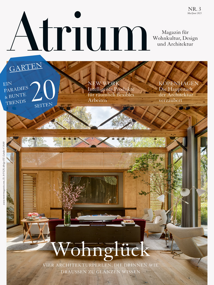 Titelbild des Magazins Atrium Ausgabe 3 von 2023 mit einem Bild eines Wohnzimmers eines grossen, lichtdurchfluteten Hauses mit Giebeldach, Holzdecke und deckenhohen Fenstern.