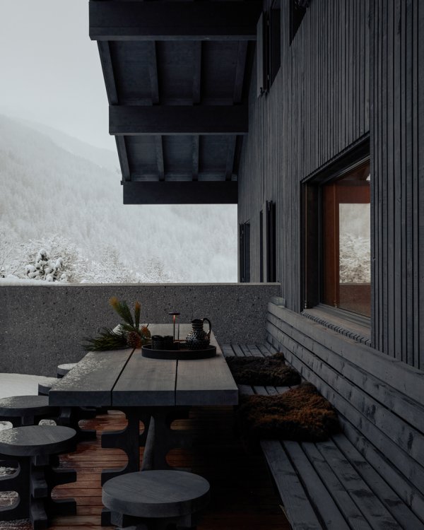Terrasse im Winter mit grossem dunklen Holztisch.