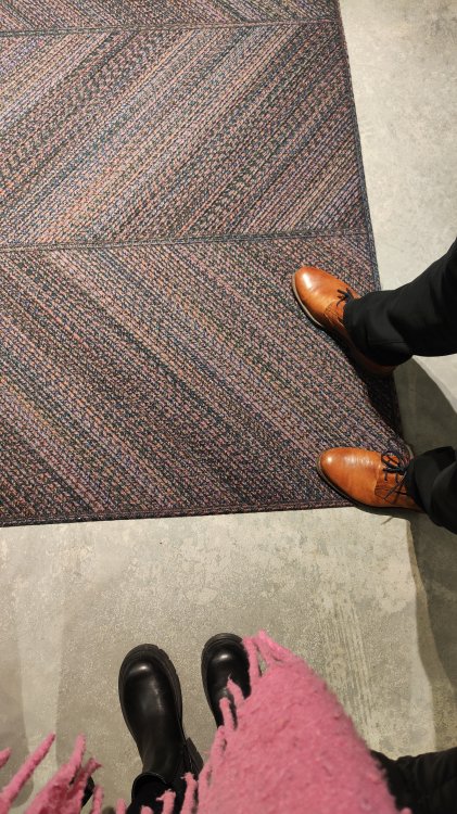 Ein Foto eines Teppichs. Auf dem Teppich stehen zwei paar Schuhe.