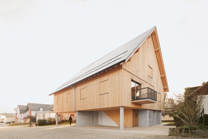 Abgebildet ist ein Holzhaus mit Satteldach in einer Einfamilienhaussiedlung.