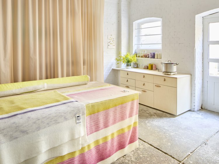 Im Atelier sind Muster der neuen Teppichkollektion in gelb-rosa Tönen ausgestellt.