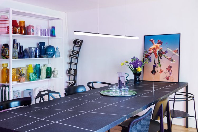 Ein Tisch steht in einem Atelier mit bunten Farben und einem Bild.