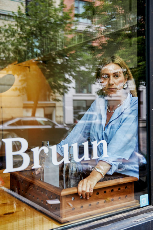 Die Designerin Maria Bruun steht hinter einem spiegelnden Schaufenster ihres Ateliers.