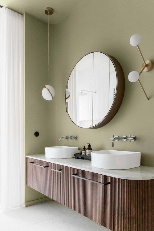Das Foto präsentiert das Badezimmer. Zu sehen. ist das Lavabo mit zwei Waschschalen und ein runder Spiegel.