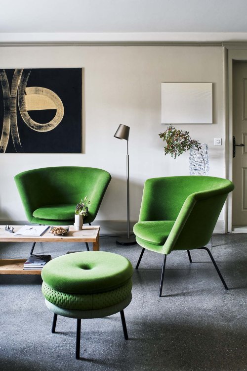 Das Foto eines Wohnzimmers, welches mit grünen Sessel ausgestattet ist.