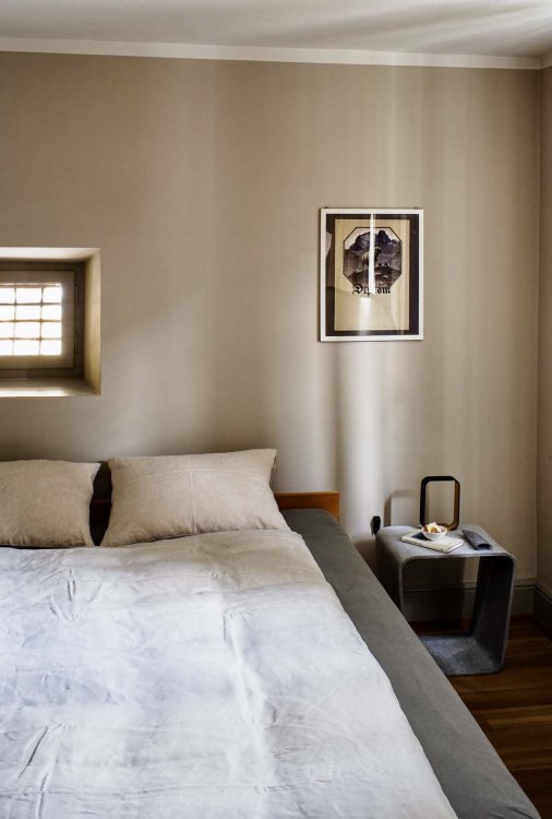 Ein Foto des Schlafzimmers. Zu sehen ist ein gemachtes Bett. neben dem Bett steht ein Nachttisch, über welchem ein kleines Bild steht.
