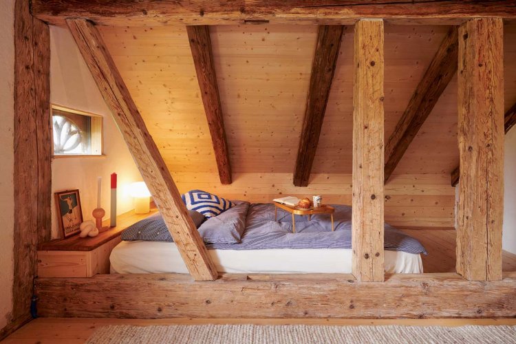 Ein Bett welches sich hinter dicken Holzbalken befindet.