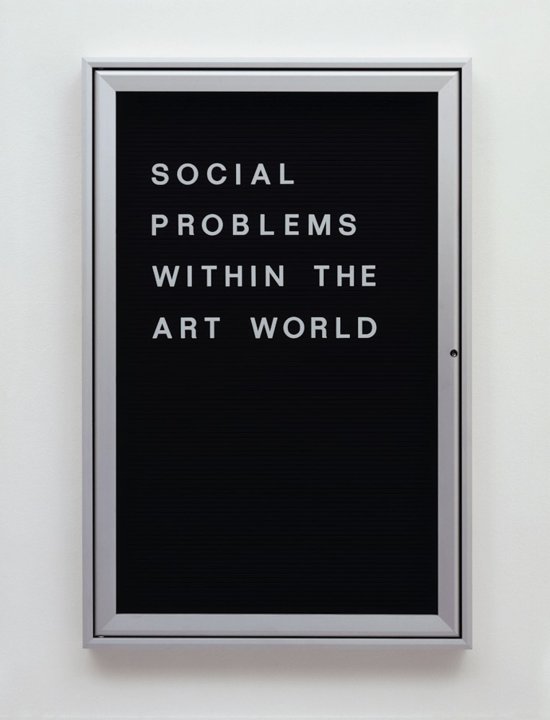Ein Glaskasten mit schwarzem Hintergrund, auf dem mit Lettern der Text "Social Problems within the Art World" geschrieben steht.