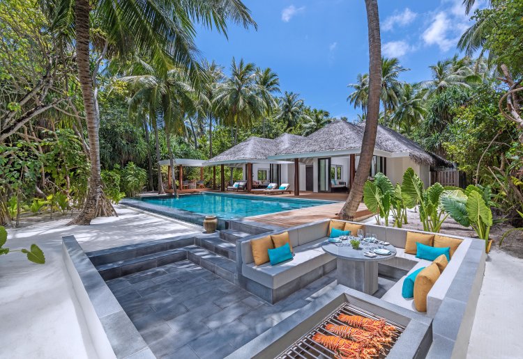 Der Aussenbereich der neuen Beach Pool Family Villas im «Anantara Kihavah Maldives Villas» Resort mit einer versenkten Sitzecke und Grill am Ende eines langen Pools.
