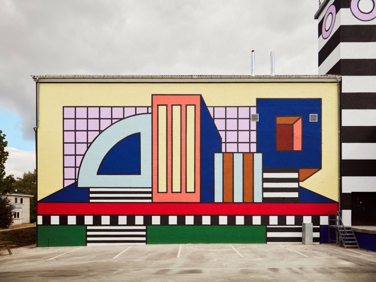 Die von der Künstlerin Camille Walala gestaltete bunte Fassade der Montana-Fabrik in Haarby, Dänemark, setzt sich aus vielen farbigen geometrischen Formen und Linien im Memphis-Stil zusammen.