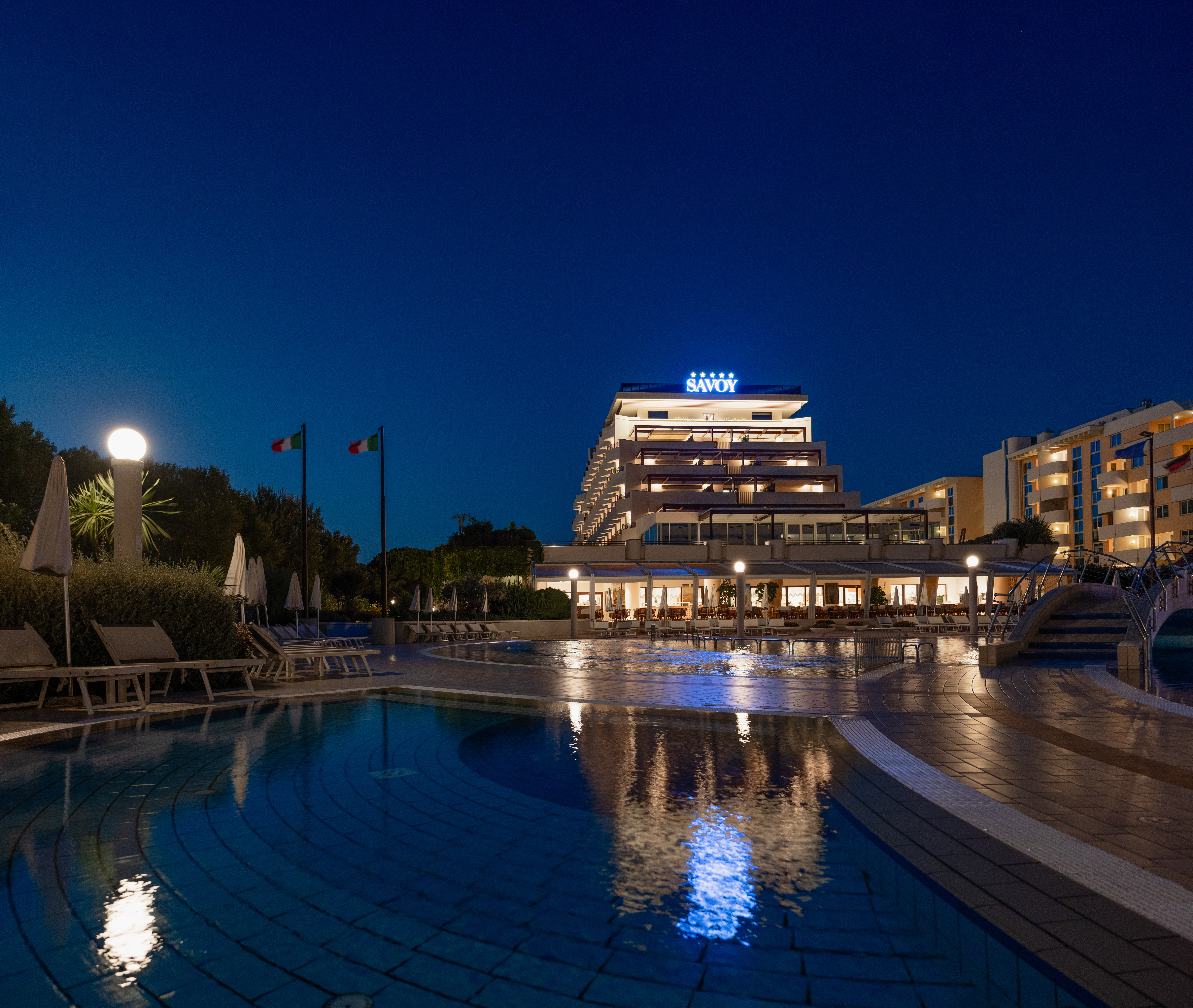 Hotelanlage des Savoy Beach Hotela bei Nacht mit Pool im Vordergrund